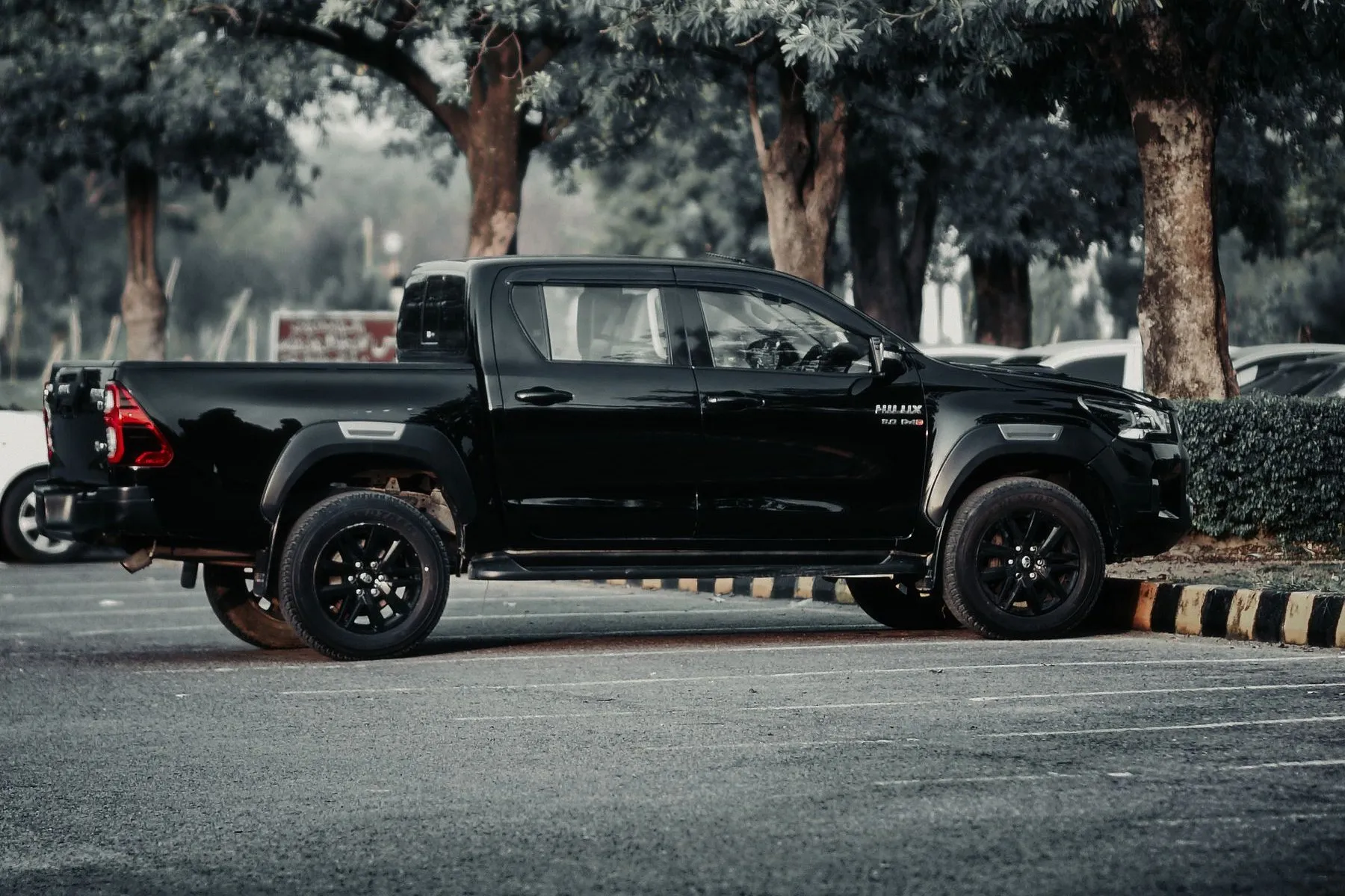 Toyota Hilux SR 2020. Toyota Hilux negra de perfil en un estacionamiento