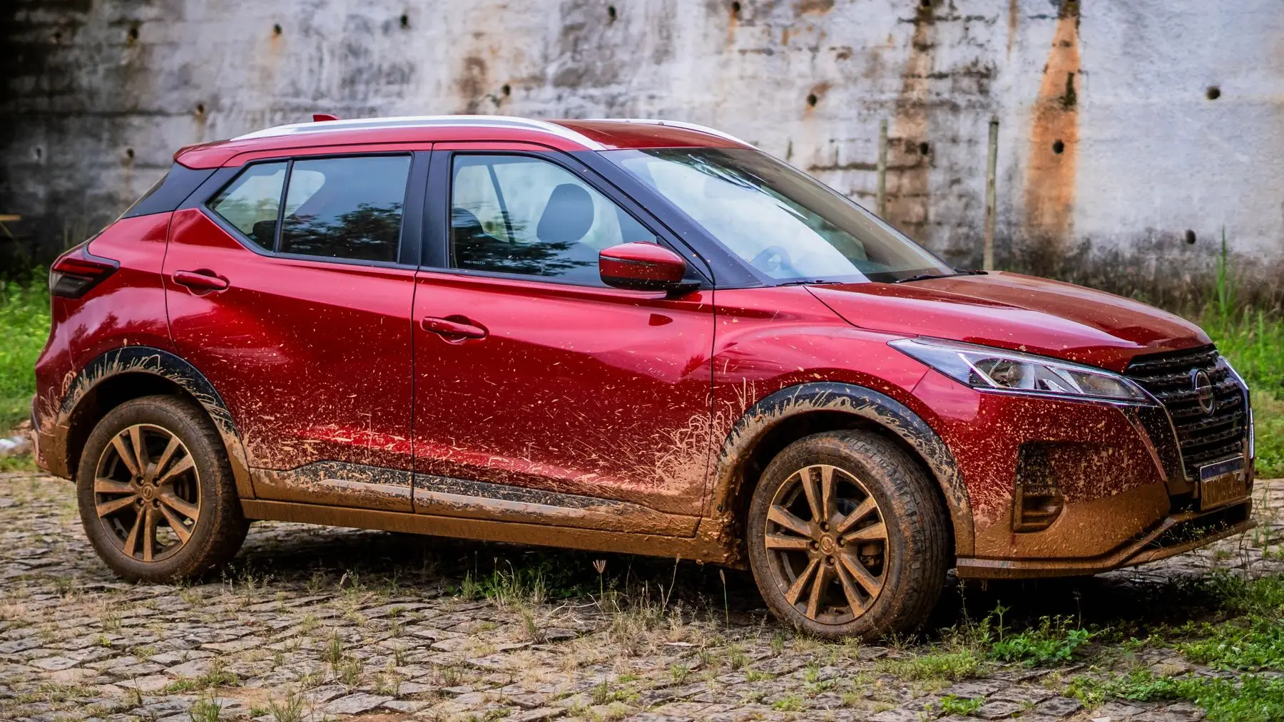 Nissan Kicks Advance 2021. Nissan Kicks roja de costado, con lodo en la carrocería